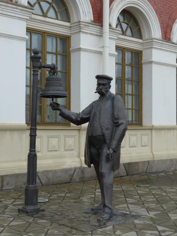 Начальник вокзала отправляет поезд ударом колокола