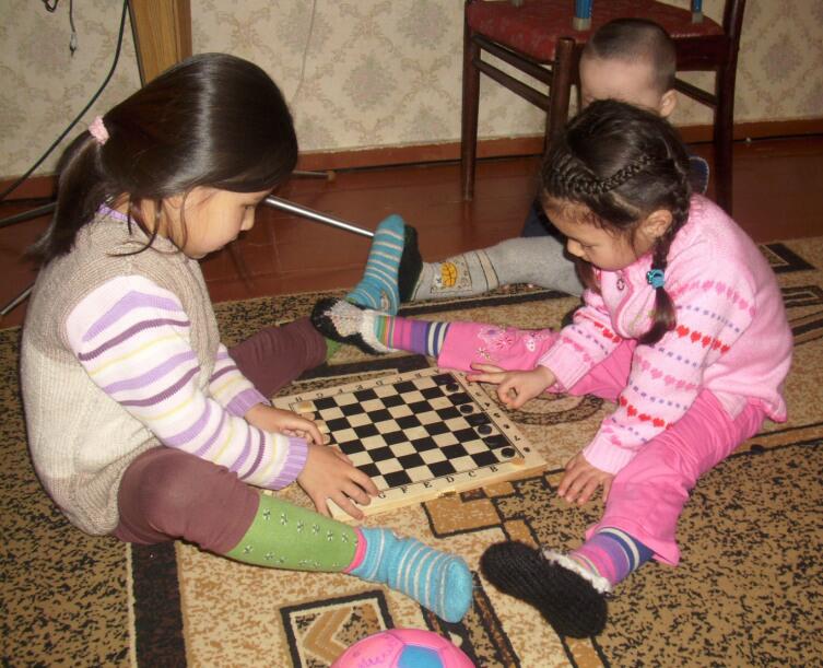 Дети играют в Чапаева. Доска повёрнута на 90° чтобы шашки не «спотыкались» о стык между половинками доски
