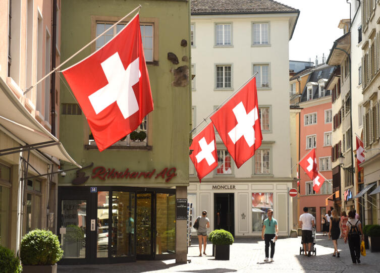 Цюрих, Швейцария - 03 июня 2017 года: Люди на улице ЦШвейцарские флаги на фасаде здания в историческом центре города Цюрих, Швейцария
