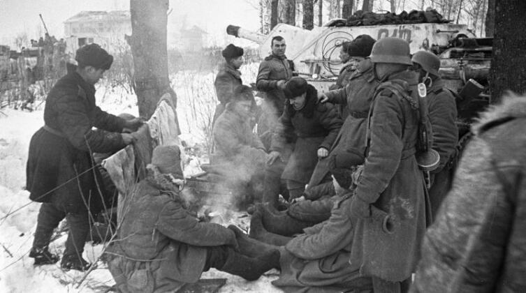 Советские самоходчики и пехотинцы отдыхают на привале в Красном селе. Операция «Январский гром». На дальнем плане справа — САУ СУ-122 из состава 1439-го самоходно-артиллерийского полка. В кадре два советских автоматчика в немецких касках М-40