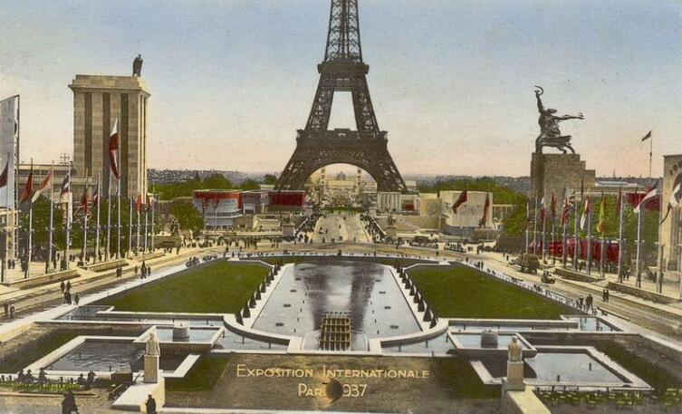 Панорама международной выставки 1937 года в Париже, в правой части — павильон СССР с «Рабочим и колхозницей», напротив — павильон Германии с орлом на крыше, по центру — Эйфелева башня
