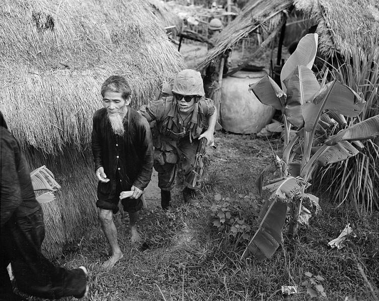 Американский морской пехотинец конвоирует вьетнамца, подозреваемого в принадлежности к НФОЮВ. Район Дананга, август 1965 г.