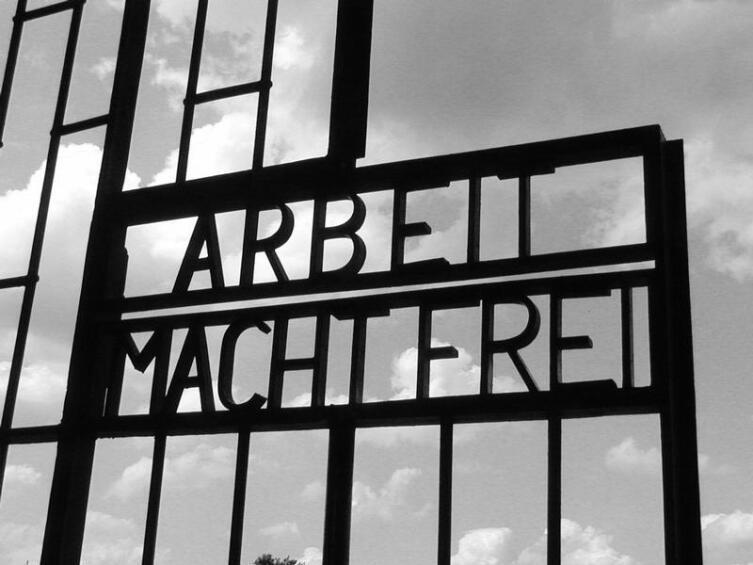 Вывеска над воротами лагеря. Фраза стала нарицательной. «Arbeit macht frei» — фраза на немецком языке, звучит как «А́рбайт махт фрай», что в переводе означает «Труд делает свободным»
