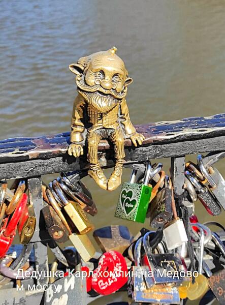 Весёлый и добродушный Дедушка Карл сидит на перилах Медового моста, свесив ножки